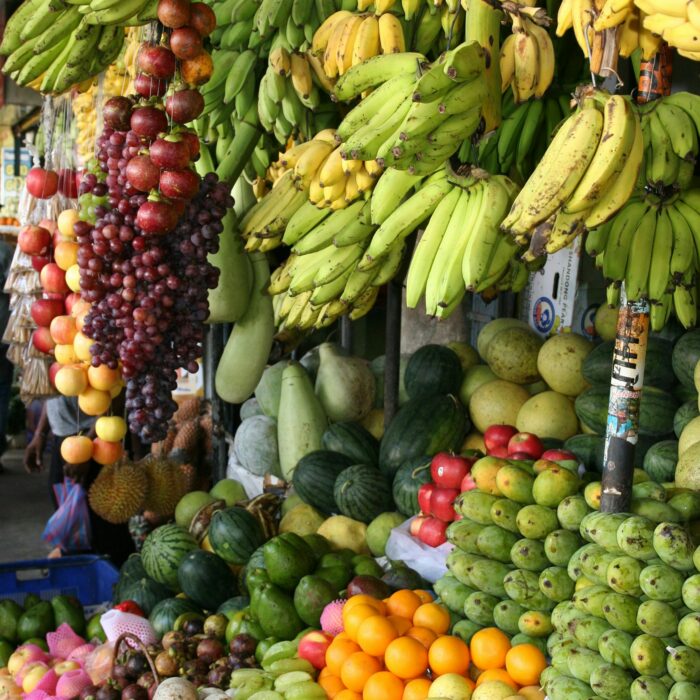 Vibrant arrangement of fresh tropical fruits at a local market, showcasing bananas, melons, and more.