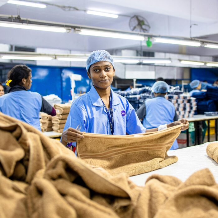 Female workers sorting towels in a busy textile factory setting.